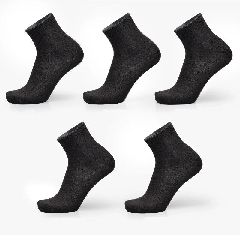 Five pairs of plain black ankle socks displayed on white background