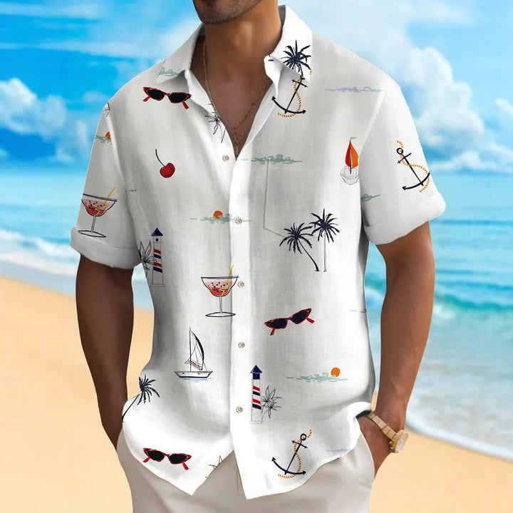 man wearing white tropical beach shirt with palm trees, anchors, cocktails, and sailboats pattern