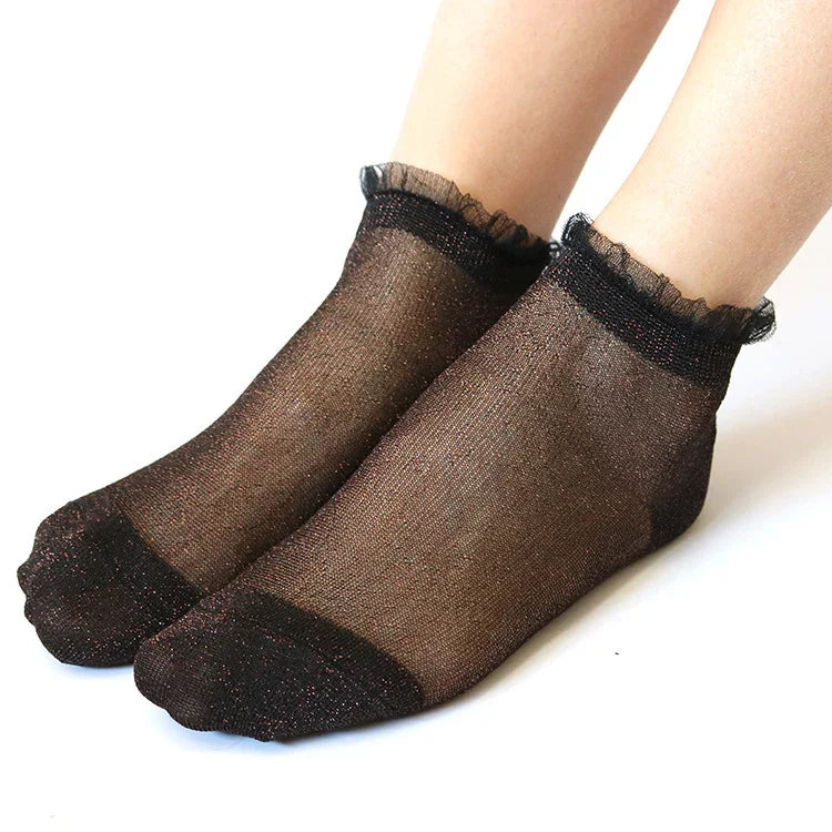 feet wearing black sheer ankle socks with ruffled edges on white background