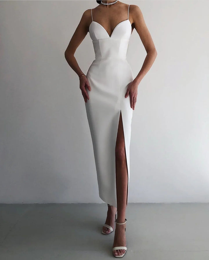 Woman wearing white sleeveless midi dress with thigh slit and white ankle strap heels