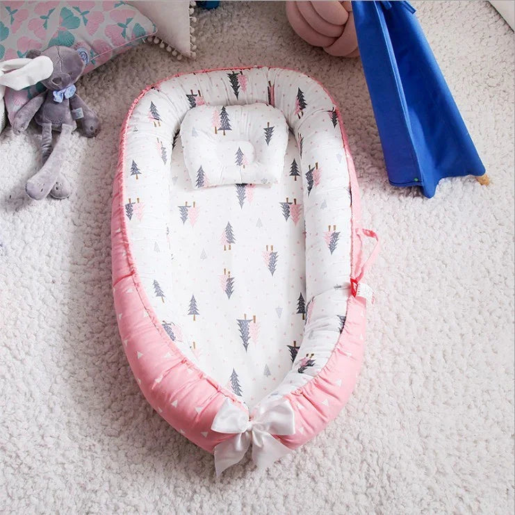 Pink and white baby nest with tree pattern and small pillow on soft white textured carpet