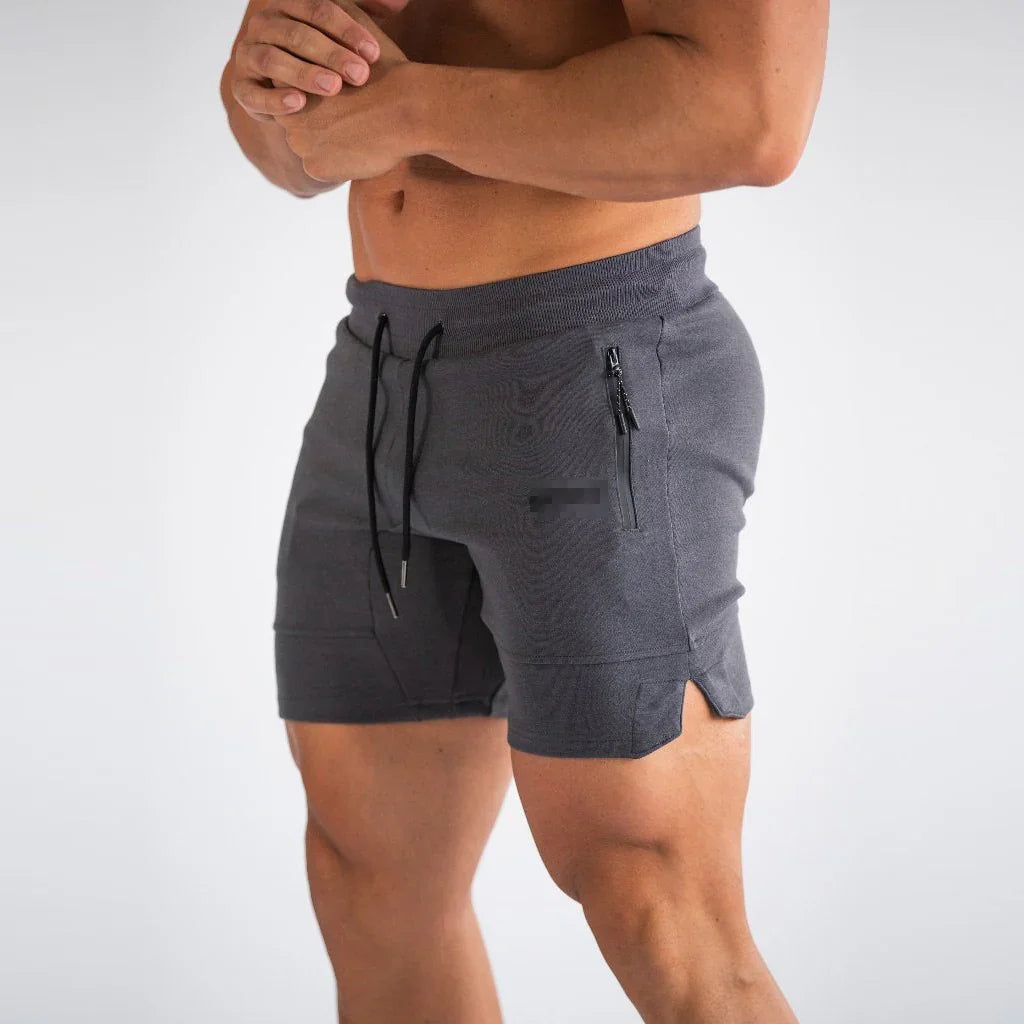 Male torso wearing dark gray athletic shorts with black zippered pocket and drawstring against white background