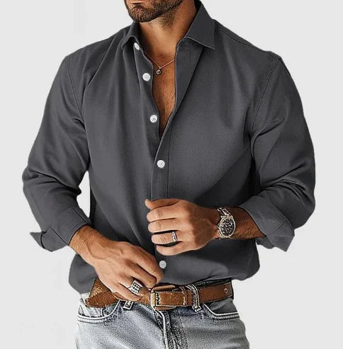 Man wearing fitted dark gray casual shirt with rolled-up sleeves, brown belt, jeans, and silver watch