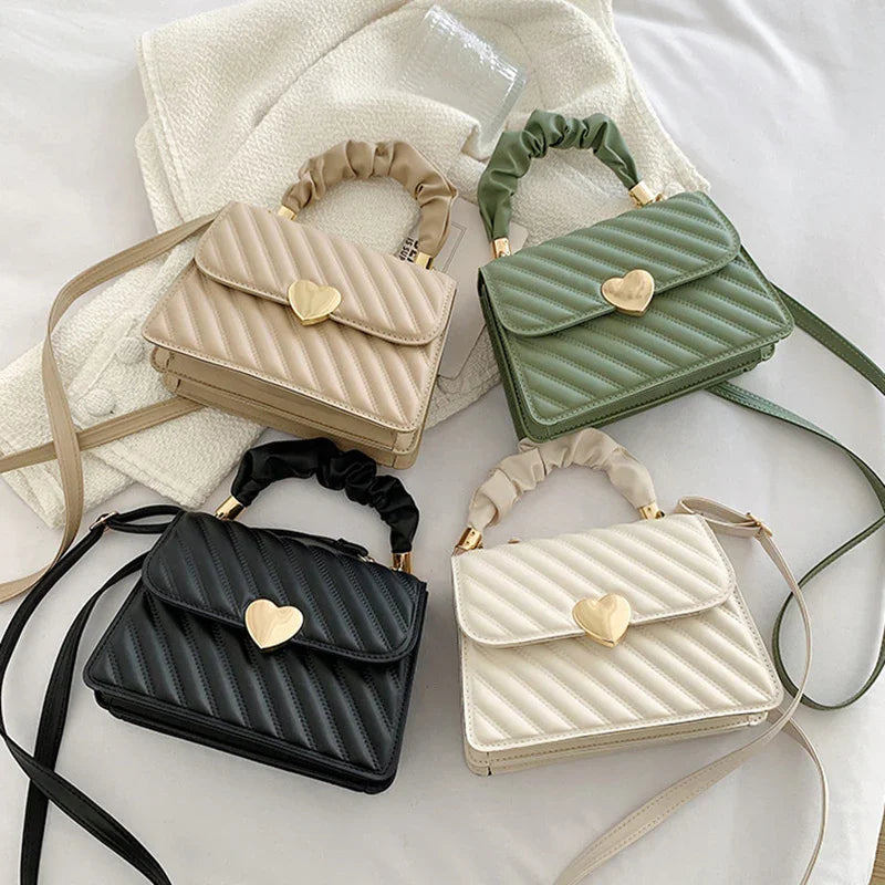 Four quilted handbags in beige, green, black, and white with gold heart clasps and scrunched handles
