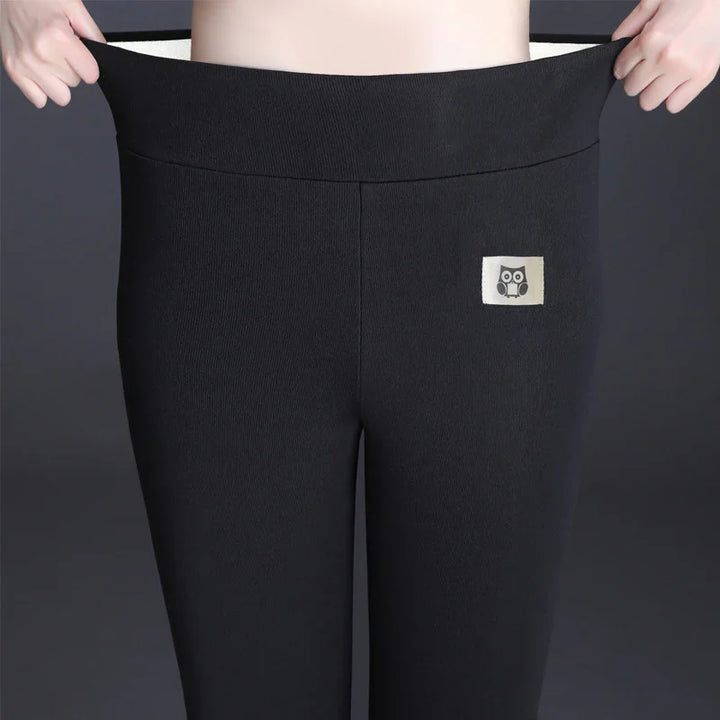 Stretchy black leggings with an owl logo patch worn on a dark background