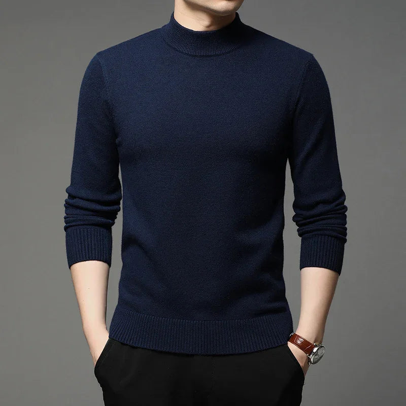 Man wearing a navy blue mock neck sweater with ribbed cuffs and hem, hands in pockets