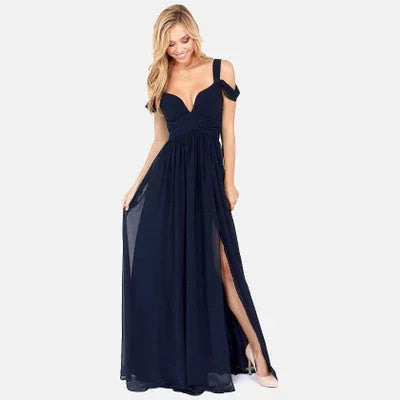 Blonde woman wearing a navy blue off-shoulder evening gown with thigh-high slit and holding skirt sides