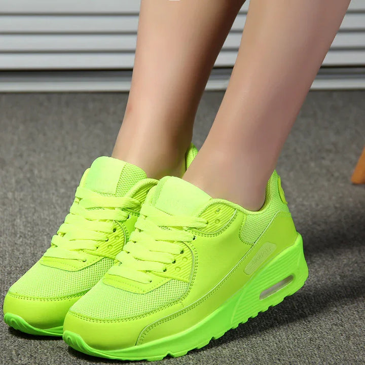 Pair of neon green athletic sneakers worn on feet with mesh and leather design on carpet