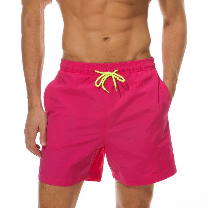 Men's bright pink swim trunks with neon yellow drawstring on shirtless model