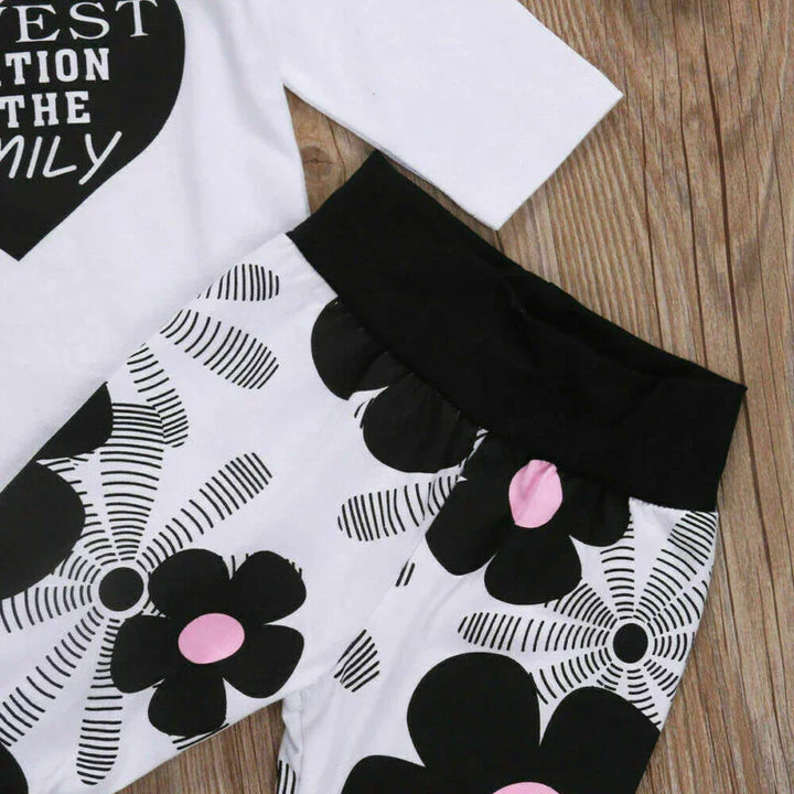 Black and white floral print leggings with pink accents and black waistband on wooden background