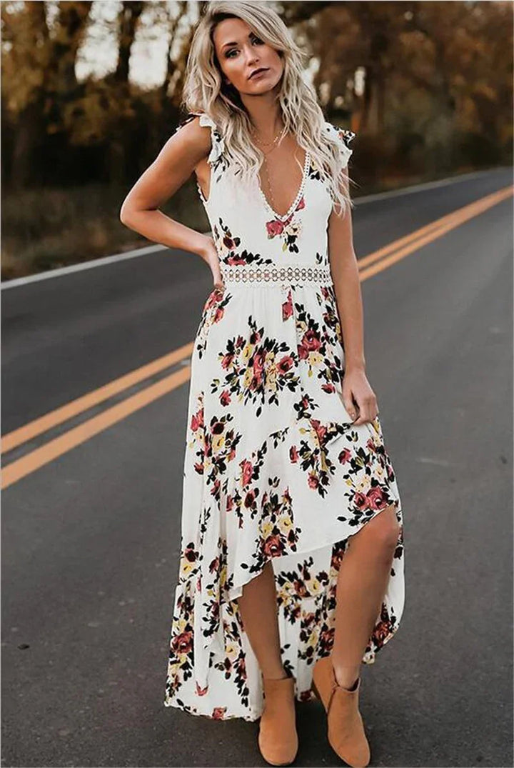 Blonde woman in white floral high-low dress and tan ankle boots standing on road with autumn background