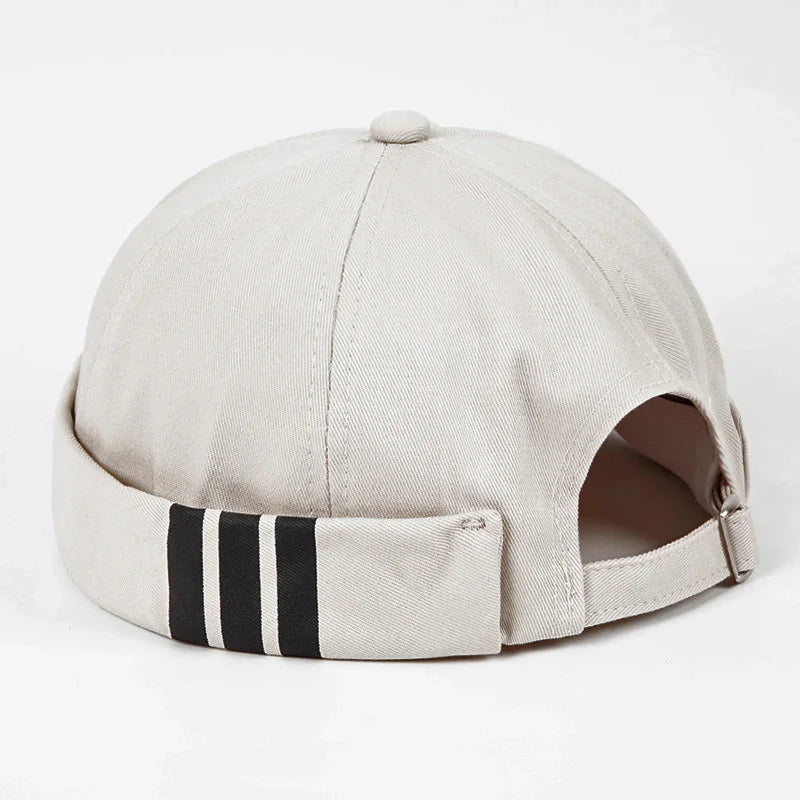 Beige casual cap with three black stripes on the rolled-up back cuff against white background