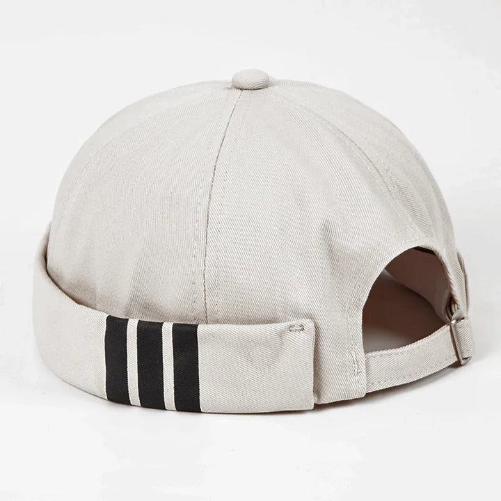 Beige casual cap with three black stripes on the rolled-up back cuff against white background