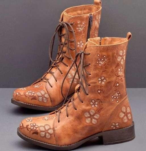 Brown leather lace-up ankle boots with floral embroidery and side zippers on a gray background
