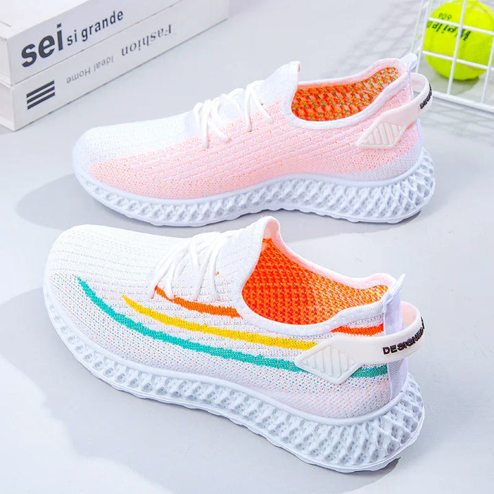 White knit sneakers with orange inner lining, colorful stripes, and textured white soles on a light surface