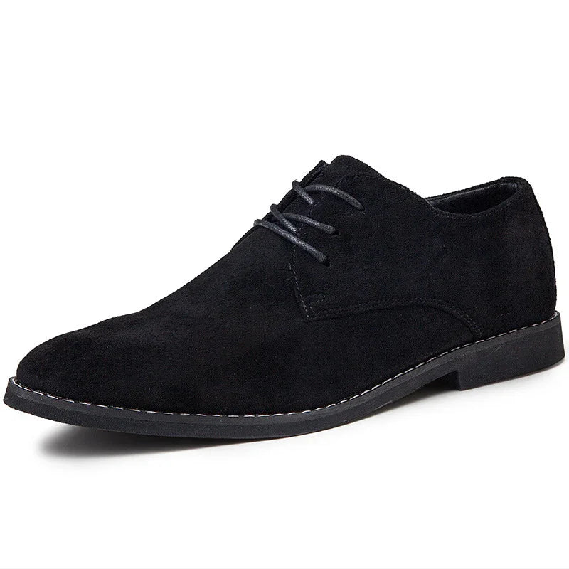 Black suede men's dress shoe with lace-up design and stitched sole on white background