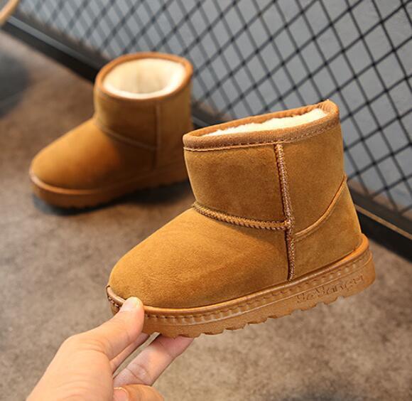Brown suede winter boots with plush interior lining held against a tiled floor and wire mesh background
