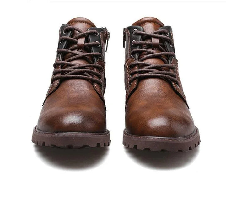 Pair of brown leather men's lace-up boots with side zippers on white background
