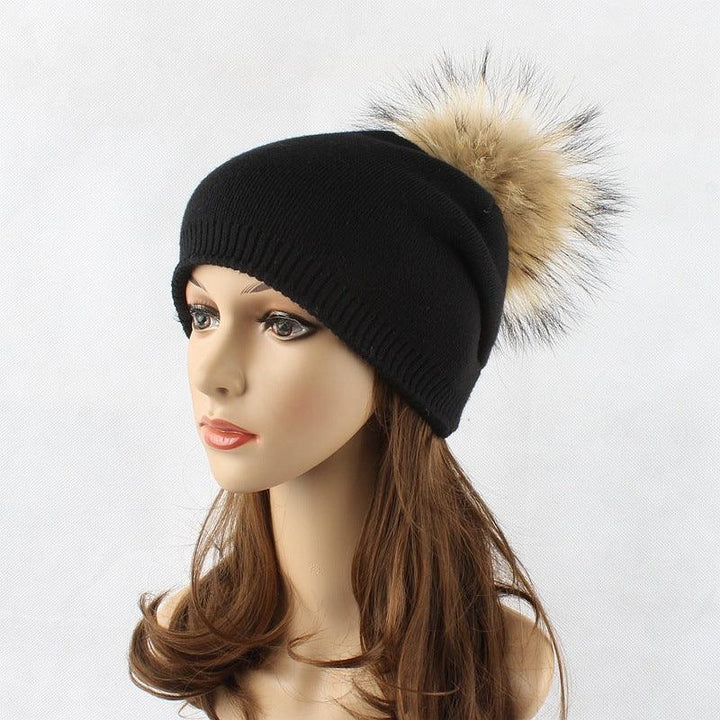 Black knit beanie with beige faux fur pom-pom on mannequin head with brown hair