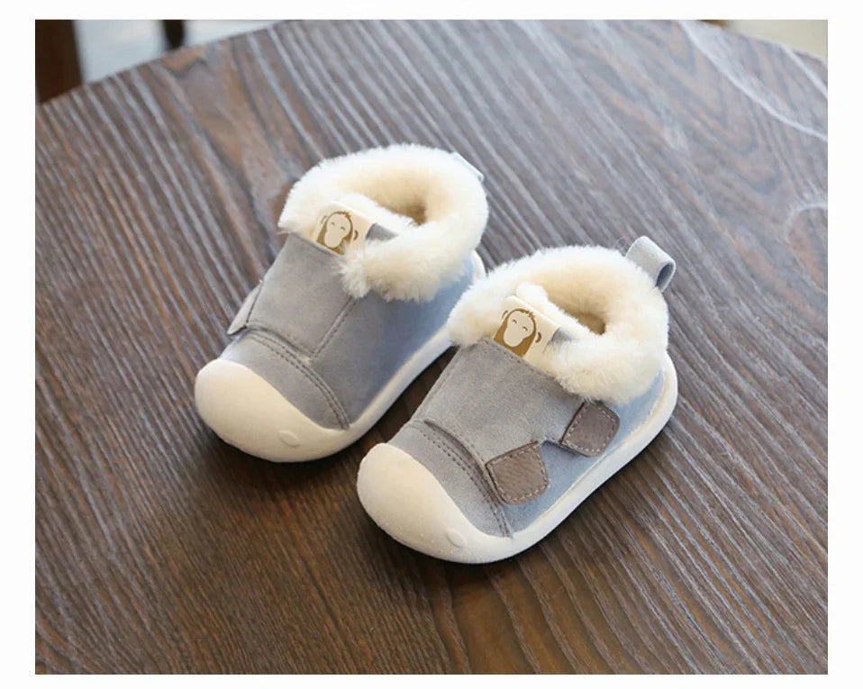 Pair of gray baby shoes with white fur lining on wooden surface