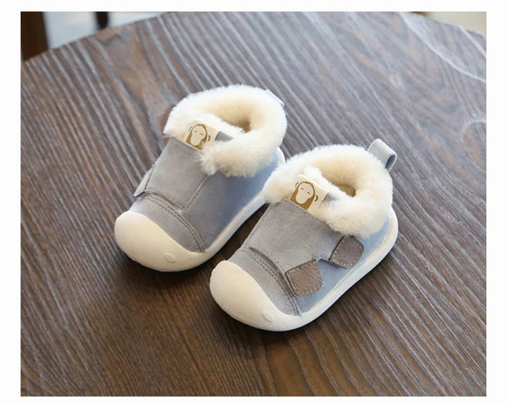 Pair of gray baby shoes with white fur lining on wooden surface