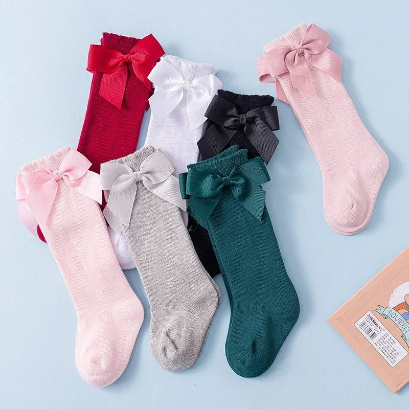 Colorful knee-high socks with large bows in red, white, black, pink, gray, and green on blue background