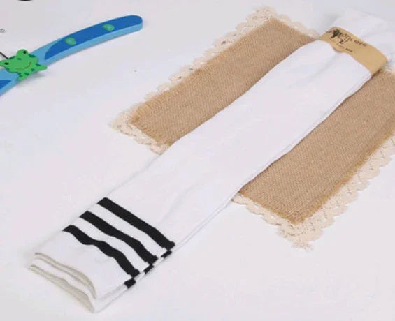 White knee-high socks with black stripes laid on a burlap and lace placemat