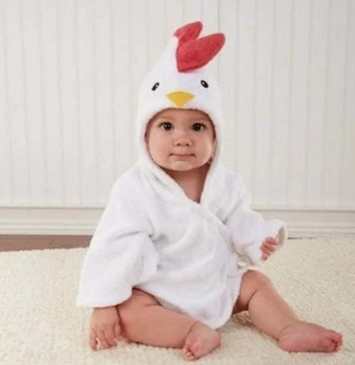 Cute baby sitting on carpet wearing white chicken costume with red comb and yellow beak