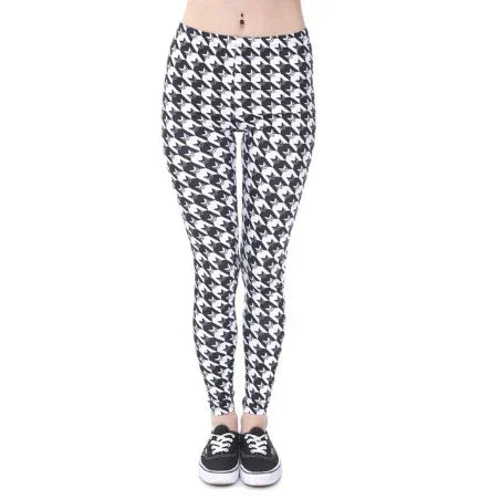 Woman wearing black and white houndstooth patterned leggings with black sneakers on white background