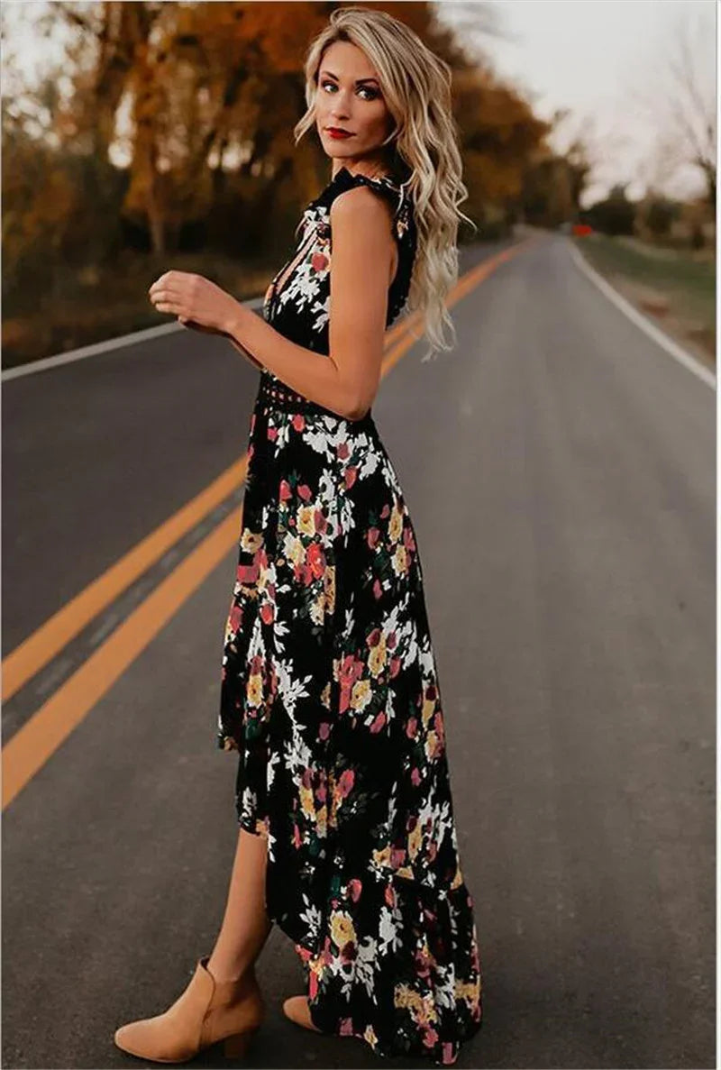 Blonde woman in black floral maxi dress and tan ankle boots standing on empty road at sunset