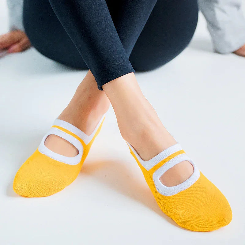 Feet wearing yellow and white no-show socks with cutout design on a white surface