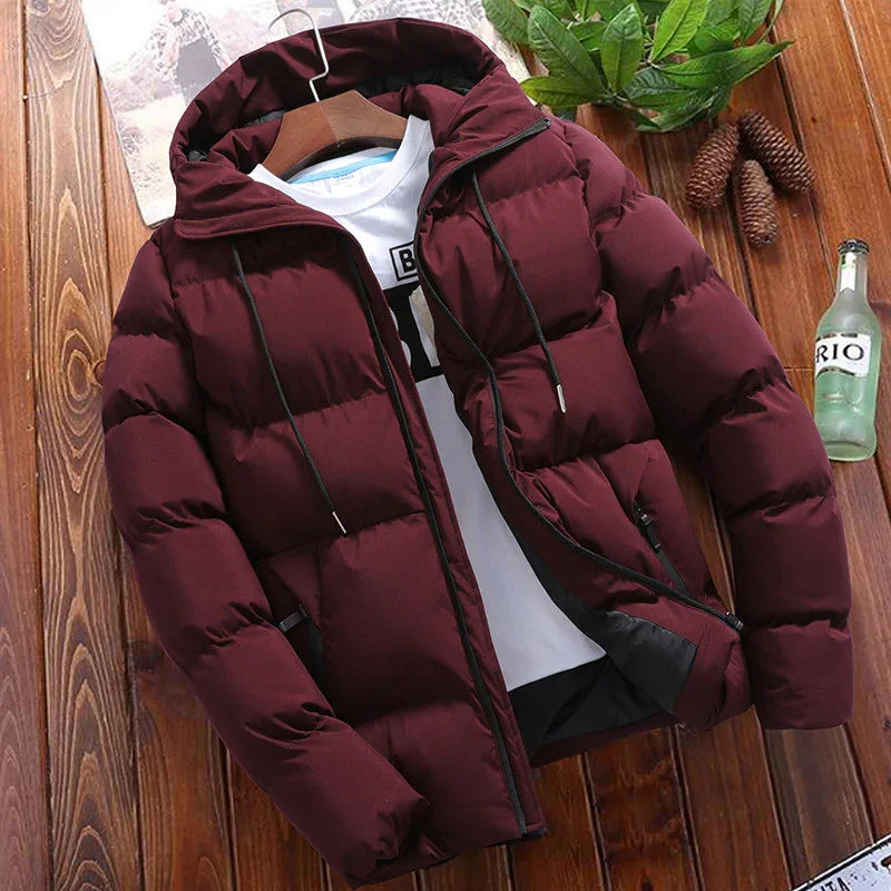Men's maroon hooded puffer jacket with black zipper and drawstrings on wooden surface