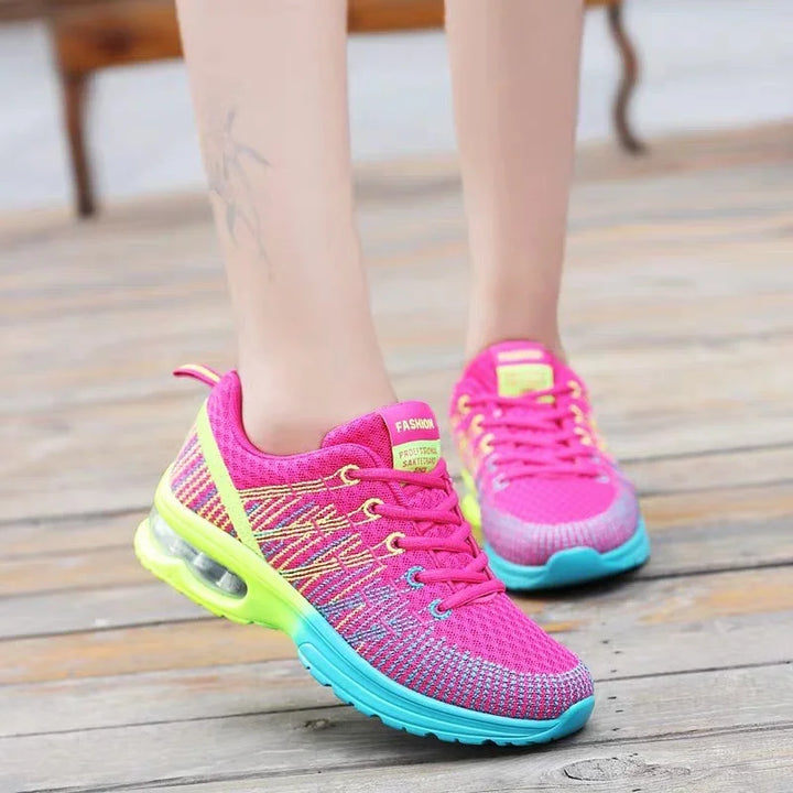 Close-up of vibrant pink and neon yellow women's running shoes with air cushion soles on wooden floor