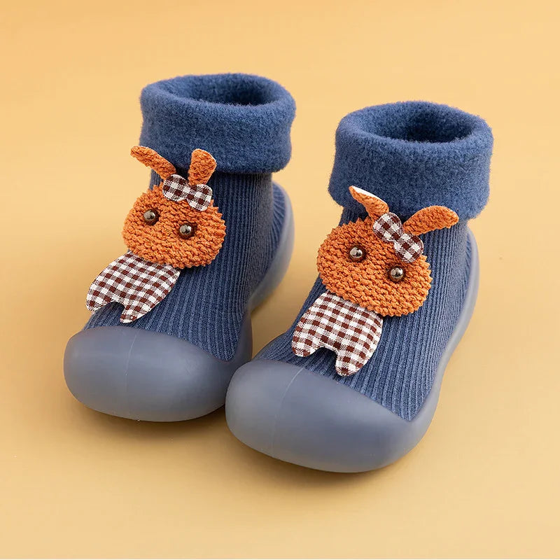 Blue baby booties with rubber soles and orange bunny decorations with checkered bows