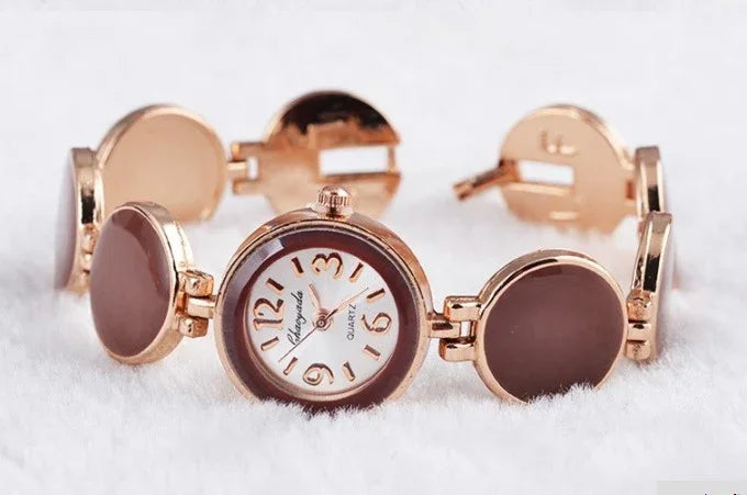 Elegant rose gold women's wristwatch with round brown enamel links on a soft white surface