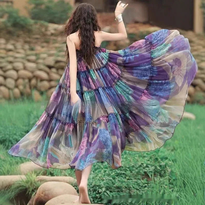 Woman in flowing multicolor purple and blue summer dress barefoot outdoors on grass