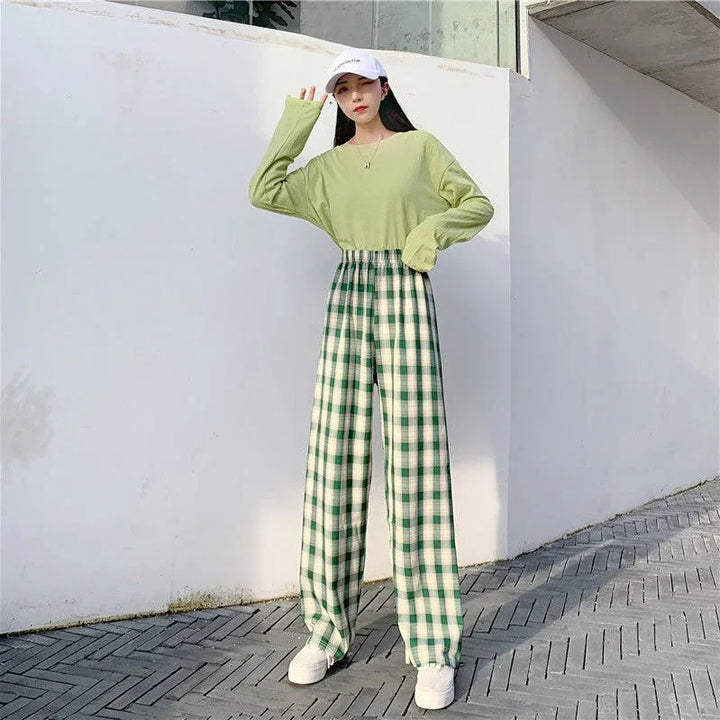 Woman wearing light green long sleeve top and high-waist green checkered wide-leg pants with white sneakers and white cap