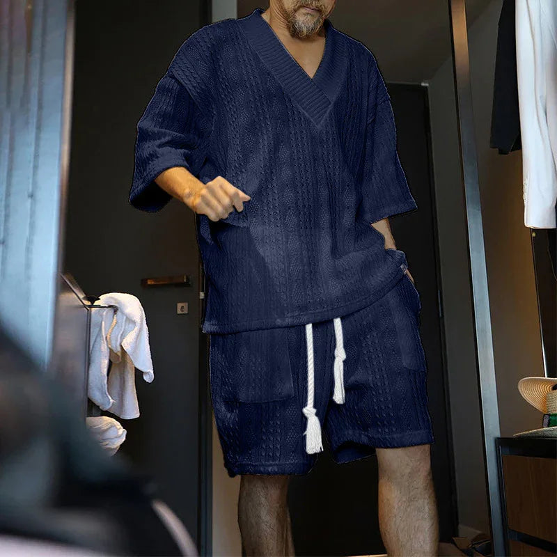 Man wearing navy blue textured knit short-sleeve top and matching shorts with white drawstrings indoors