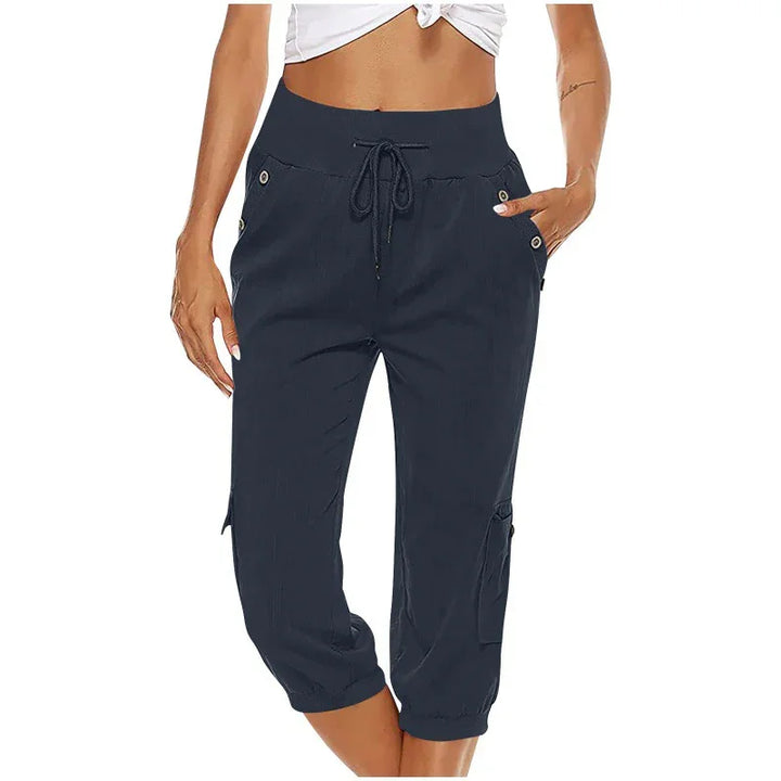 Woman wearing navy blue cropped cargo pants with drawstring waist and buttoned pockets