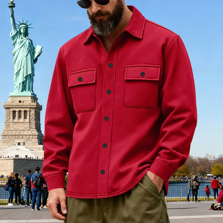 Man wearing red button-up shirt and sunglasses near Statue of Liberty on sunny day