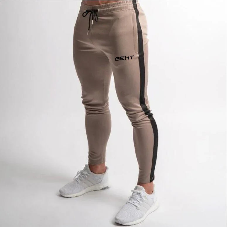Men's beige slim fit joggers with black side stripe and drawstring waist, paired with white sneakers