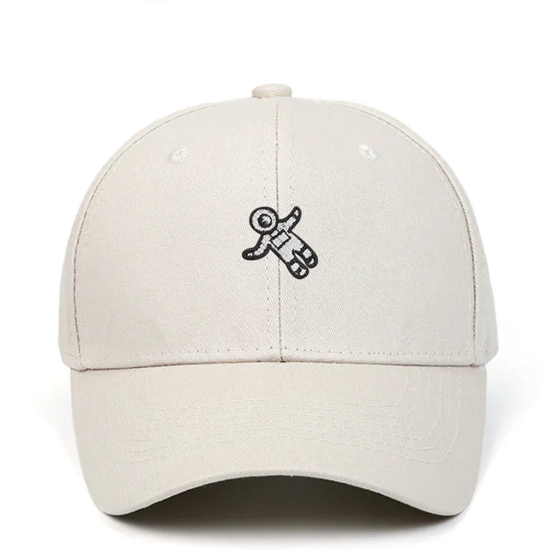 Beige baseball cap with small black astronaut embroidery on front center