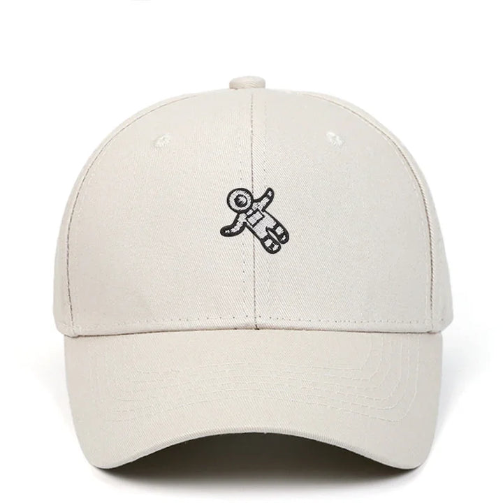 Beige baseball cap with small black astronaut embroidery on front center
