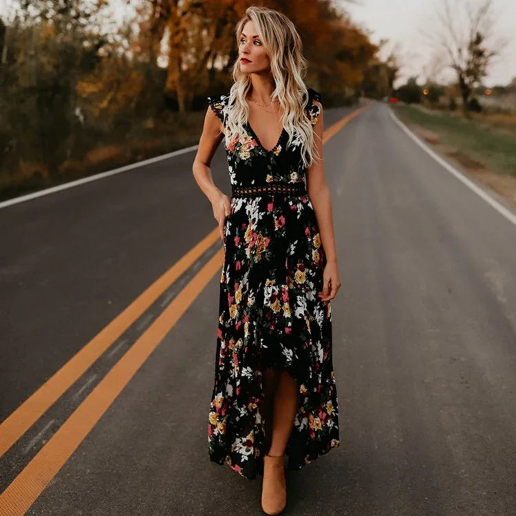 Blonde woman in a black floral maxi dress standing on an empty two-lane road with autumn trees