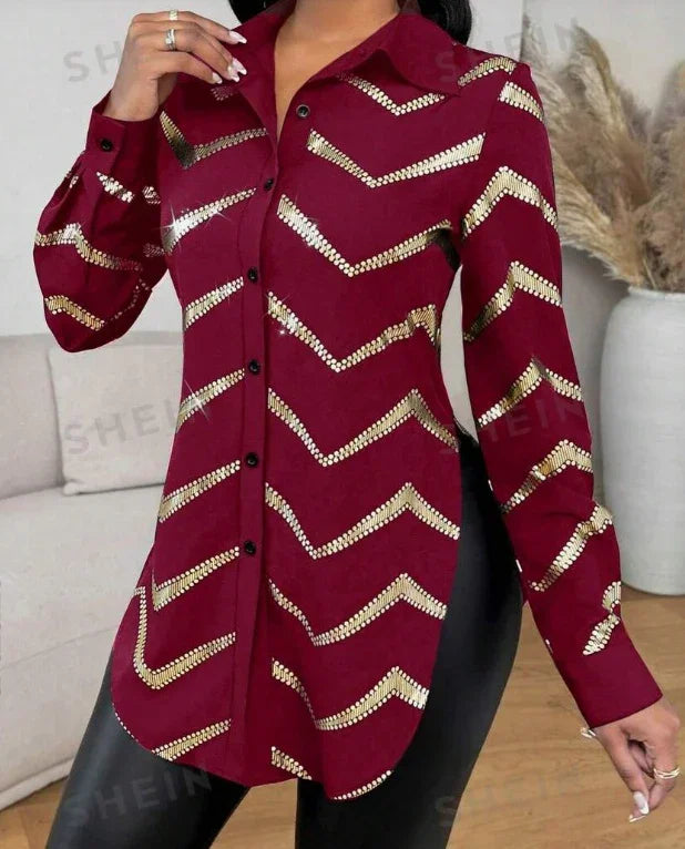 Woman wearing a burgundy button-up shirt with gold sequin chevron stripes and black pants indoors