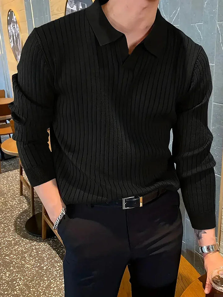 Man wearing a black ribbed long-sleeve polo shirt paired with black pants and a belt indoors