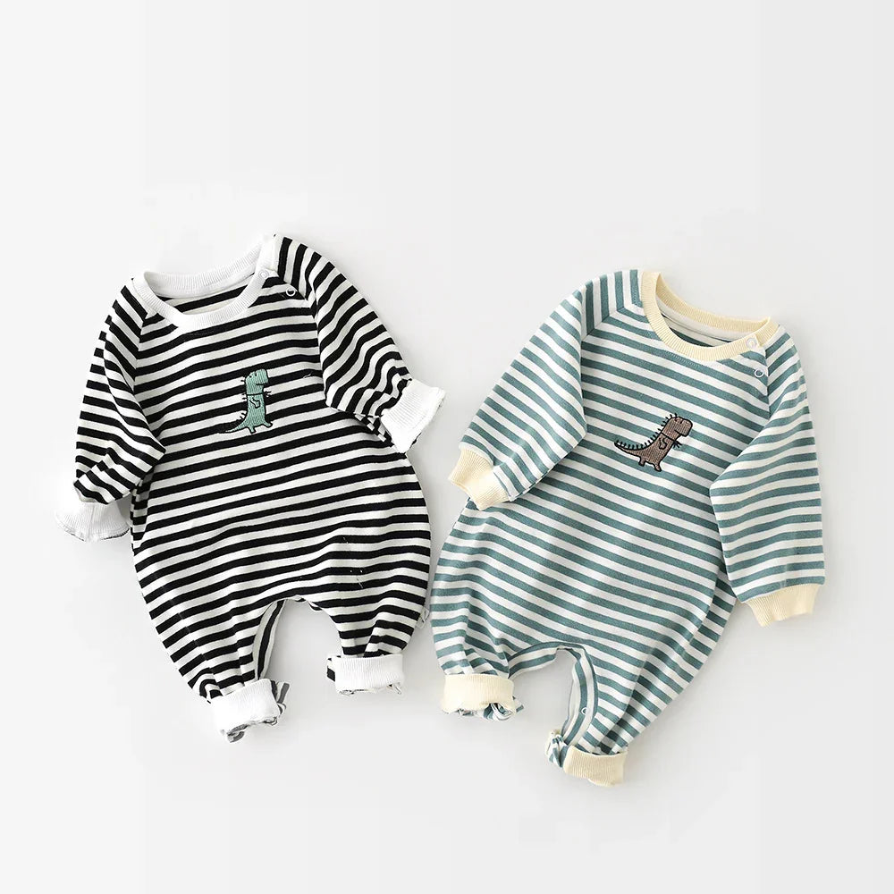 Two striped baby rompers with dinosaur embroidery, one black-white and one blue-white, laid flat on white background