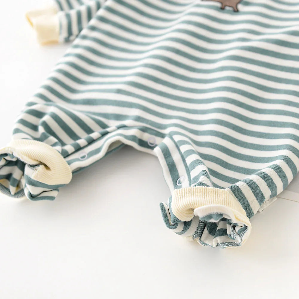 Close-up of striped green and white baby romper with cream cuffs and snap buttons