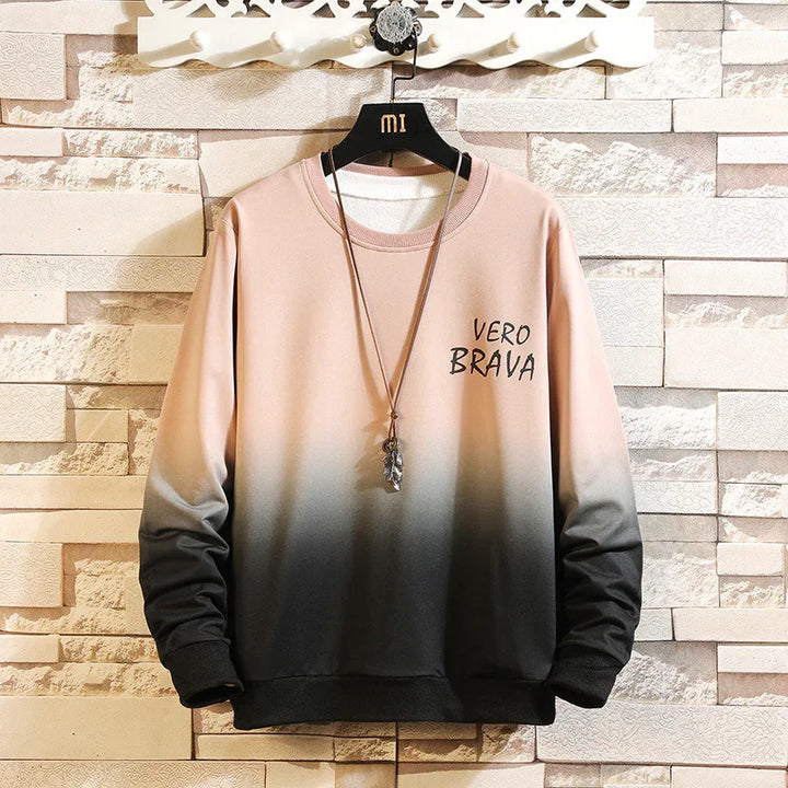 Gradient pink to black sweatshirt with VERO BRAVA text, displayed on black hanger against stone wall