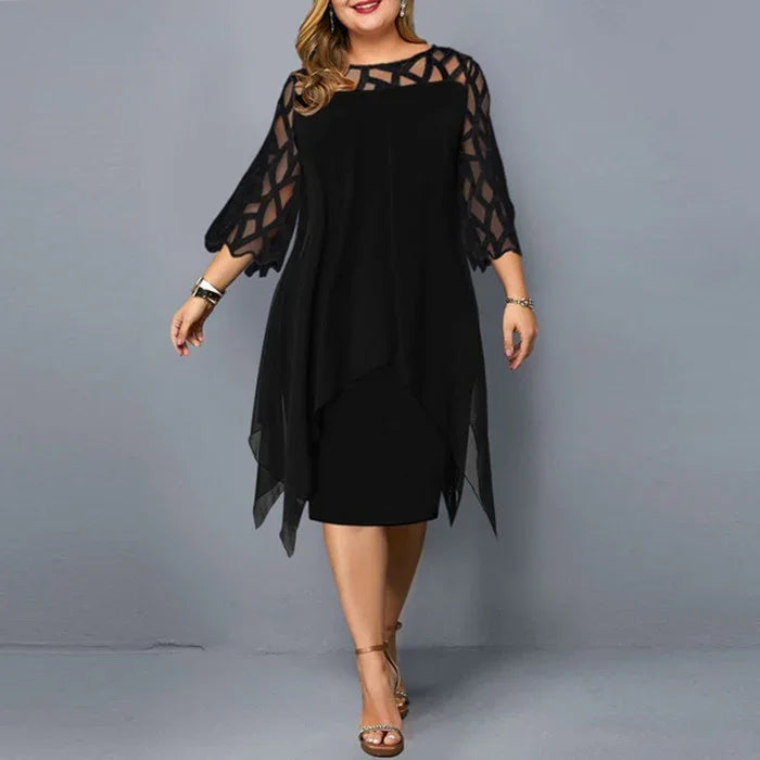Plus size woman wearing a black dress with sheer geometric patterned sleeves and asymmetrical hem